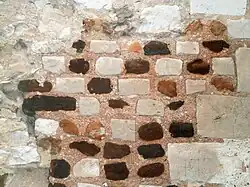 Photographie en couleurs d'un mur dont les pierres dessinent des motifs géométriques.