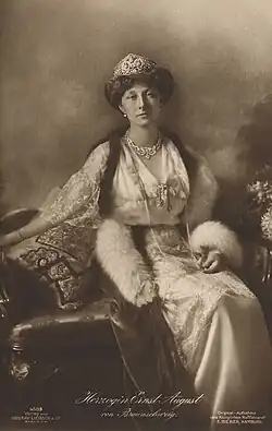 Photographie en noir et blanc d'une femme assise portant une tenue de fête et des bijoux