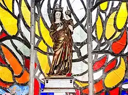 Vierge à l'Enfant, devant le vitrail flamboyant du chœur de la basilique.