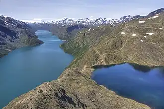 Grand lac allongé aux eaux turquoises vu depuis une arrête rocheuse près d'un petit lac.