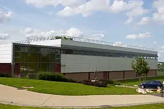 Vue d'un grand bâtiment en panneaux ondulés et en verre ; toit en terrasse.