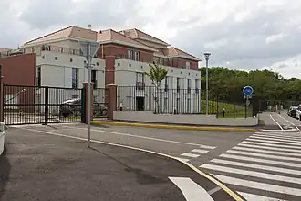 Vue d'un petit immeuble collectif dans une résidence ; alternance de panneaux pierre et brique.