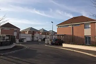 Vue d'une résidence pavillonnaire moderne ; bâtiments de même modèle alternant pierre et brique.