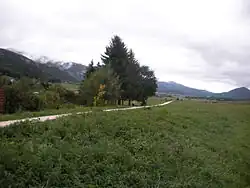 Paysage d'une vallée avec au premier plan un chemin et au fond des montagnes.