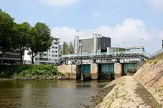 Le barrage-écluse donnant sur la Loire. Vue Aval, avec passerelle piétons, traces des différents niveaux du fleuve sur les vannes. Porte levante de l'écluse et portique de levage à gauche