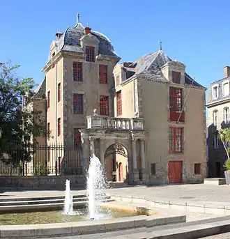 Vue d’un édifice formant deux corps de bâtiment, à 3 étages, à la façade bistre.