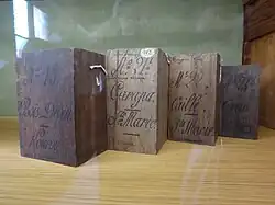 Quatre blocs de bois portant chacun un numéro, un nom vernaculaire et une localité calligraphiés.