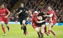 Photographie de cinq joueurs de rugby à XV durant un match.