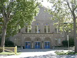 Un grand bâtiment en briques grises entouré d'arbres.
