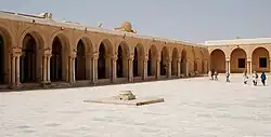 Photographie du portique occidental de la cour, ouvert par des arcades outrepassées brisées. Son extrémité nord est marquée par deux arcades aveugles.