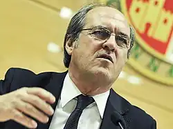 Homme grisonnant portant des lunettes pronoçant un discours.