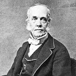 Photographie en noir et blanc d'un homme âgé en costume et de trois quarts face.