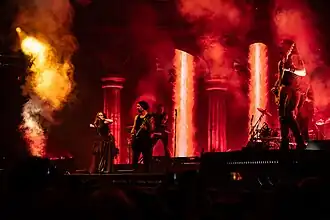 Six membres d'un groupe de metal jouant sur une scène éclairée de rouge