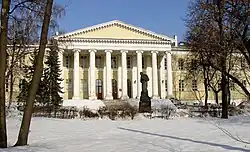 Large façade beige clair à colonnes éclairée par la lumière d'un ciel bleu en hiver