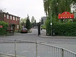 Photo de l'entrée d'un établissement scolaire avec un bâtiment en briques rouges sur la gauche.