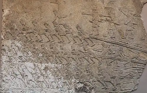 Des ouvriers tirent des cordes tractant une statue de taureau ailé, bas-relief du Palais sud-ouest de Ninive (début VIIe&nbsp;siècle&nbsp;av. J.-C.). British Museum.