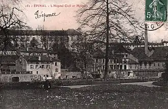 L'hôpital Saint-Maurice dont le clocher est visible derrière la cheminée d'usine à droite ; à gauche le grand bâtiment, plus récent, qui sera épargné par la guerre.