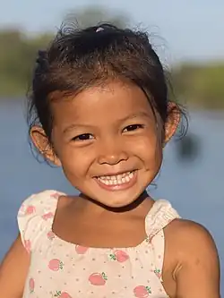 Petite fille de l'île, souriante, au soleil à l'heure dorée.