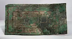 Plaque rectangulaire de cuivre oxydé, gravée de formes rectangulaires.