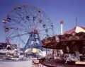 Une grande roue et deux manèges d'un parc d'attractions.